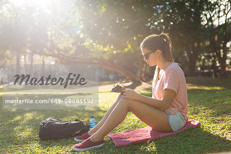 Young woman reading magazine in park, Manila, Philippines