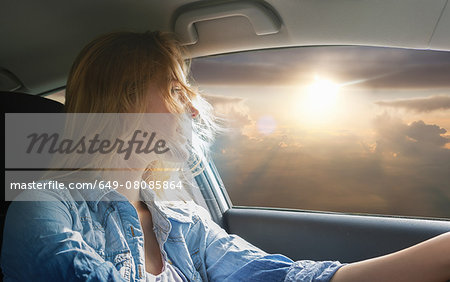 Woman driving car and watching sunset