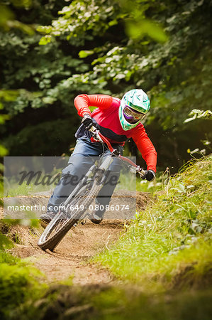 Young woman downhill mountain biking in forest