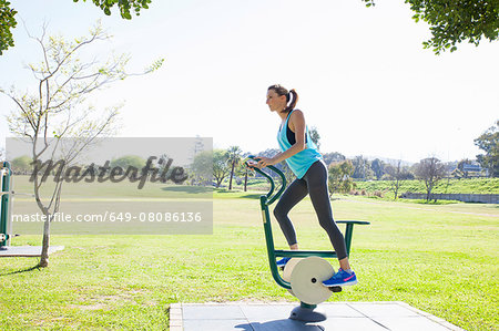 Mid adult woman training on exercise bike in park