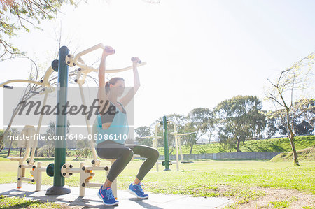 Mid adult woman training on weight machine in park