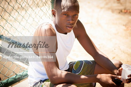 Portrait of young male basketball player with smartphone and drinking water