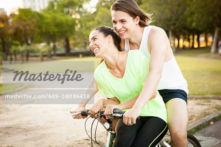 Young couple cycling pillion in park