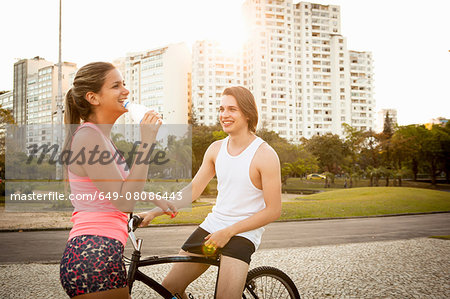 Young couple chatting whilst preparing to cycle in park