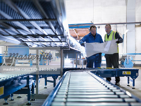 Engineers inspecting new conveyor in engineering factory