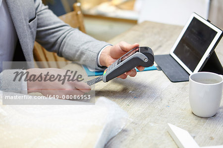 Man buying online with credit card in picture framers workshop
