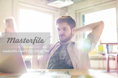 Casual businessman working at laptop in sunny office