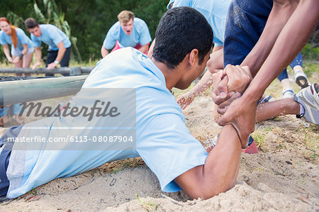 Teammate helping man on boot camp course
