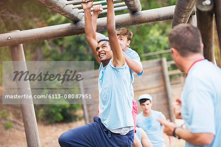 Man crossing monkey bars on boot camp obstacle course