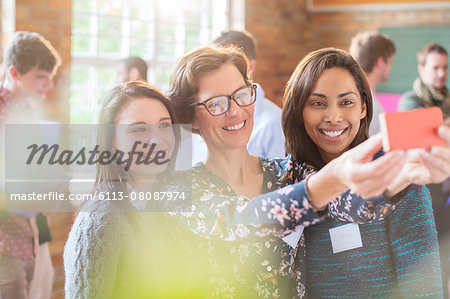 Women taking selfie with camera phone in community center Women taking selfie with camera phone in community center