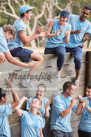 Team clapping and celebrating at wall on boot camp obstacle course