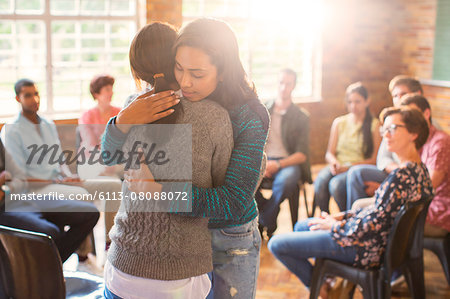Women hugging in group therapy session Women hugging in group therapy session