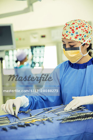 Surgeon arranging surgical scissors on tray in operating room