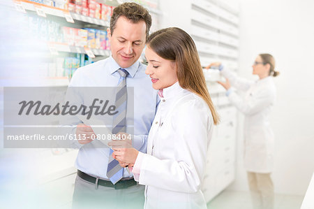 Pharmacist and customer reviewing prescription in pharmacy Pharmacist and customer reviewing prescription in pharmacy