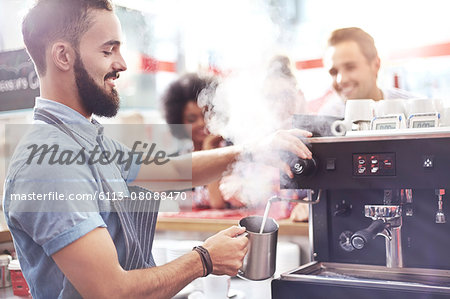 Barista steaming milk in cafe