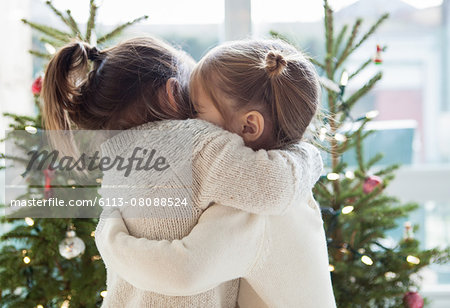 Girls hugging in front of Christmas trees