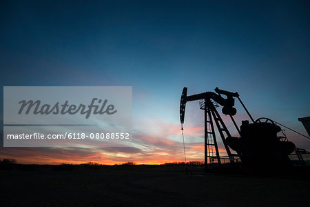 A pumpjack at an oil drilling site at sunset. A pumpjack at an oil drilling site at sunset.