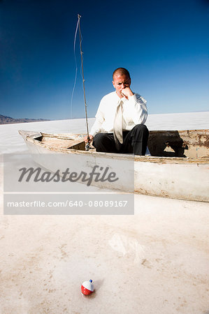 businessman fishing from a boat in the middle of the desert