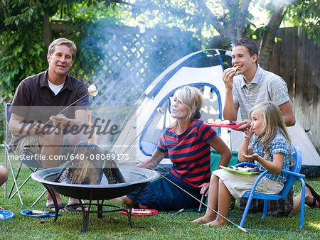 family roasting marshmallows in the backyard