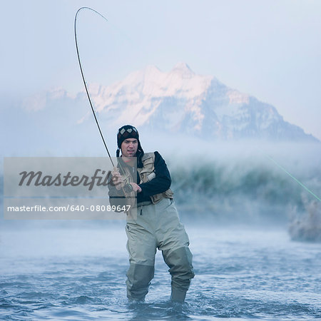 fly fisherman fishing in a mountain river