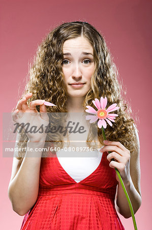 woman pulling off the petals of a daisy