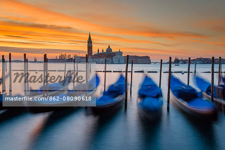 Moored gondolas with San Giorgio Maggiore island in the background at sunrise, Venice, Veneto, Italy