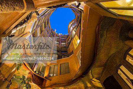 Bottom view of the inner courtyard of Casa Mila or La Pedrera at dusk, Barcelona, Catalonia, Spain