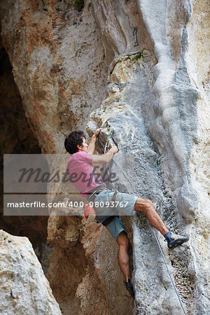 female rock climber climbs on a rocky wall