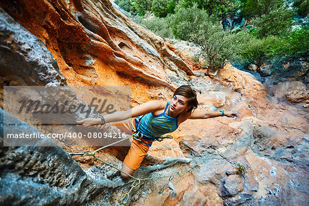 female rock climber climbs on a rocky wall