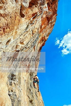 male rock climber climbs on a rocky wall