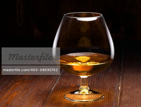 Luxury still life with glass of cognac, on a wood background. Front view with copyspace. Close up shot