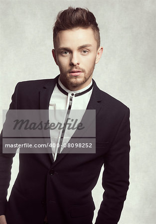 young male model looking in camera with fashionable expression , he is wering a black trendy jacket