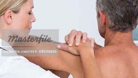 Doctor examining her patient shoulder in medical office