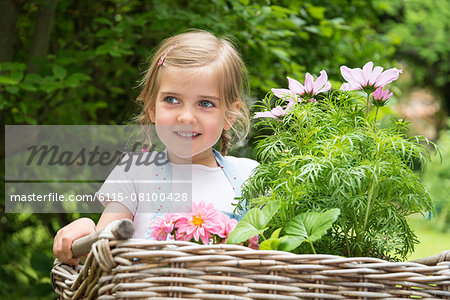 Girl gardening, carrying flowers in basket