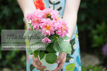 Girl gardening, holding pot with flowers