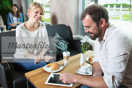 Couple dating in a cafe, man using digital tablet