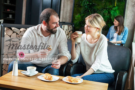Couple flirting in a cafe, people in background