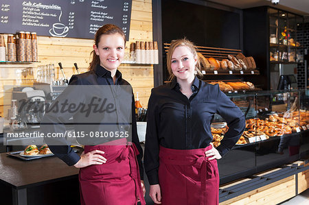 Female shop assistants in coffee shop standing side by side