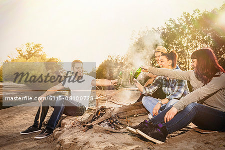 Group of friends toasting with beer by campfire, Osijek, Croatia