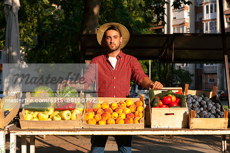 Young man selling fruit and vegetables at market stall