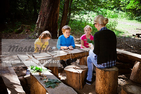 Children and teacher crafting in forest camp, Munich, Bavaria, Germany