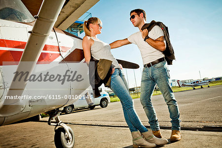 Young couple leaning against propeller airplane