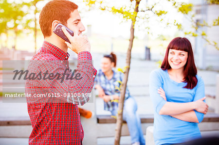 Young man using phone, friends in background, Osijek, Croatia