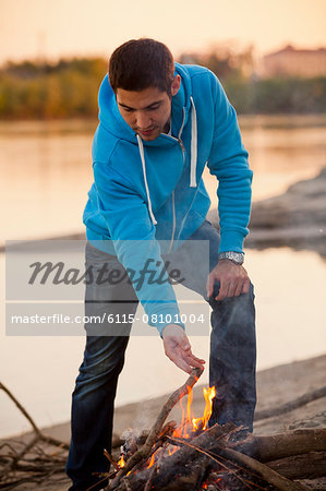 Young man arranging firewood at campfire, Osijek, Croatia
