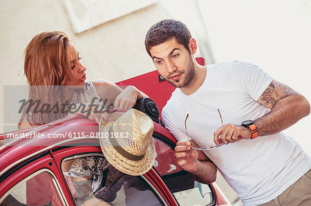 Young couple preparing for road trip in red car