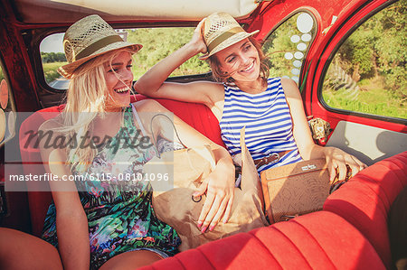 Two women on back seat of vintage car laughing happily