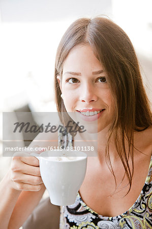 Young woman with brown hair having a cappuccino