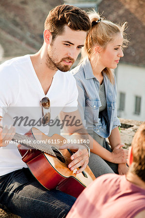 Young man playing guitar at rooftop party