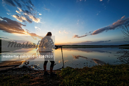 Hiker by Calm Lake at Sunset, Saskatchewan, Canada Hiker by Calm Lake at Sunset, Saskatchewan, Canada