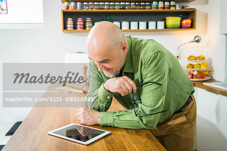 Senior man in kitchen using digital tablet